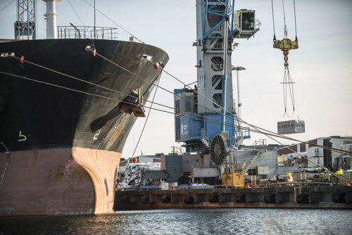 Hamnmiljö med lastfartyg och kranar.