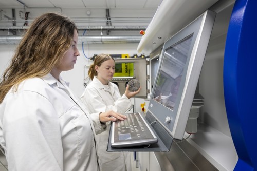 Två personer i vita rockar vid en datorskärm.