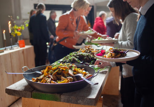 Buffé och personer som står i kö för att ta mat på tallrikar.