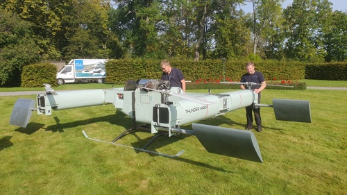 En stor drönare som två personer står och håller i.